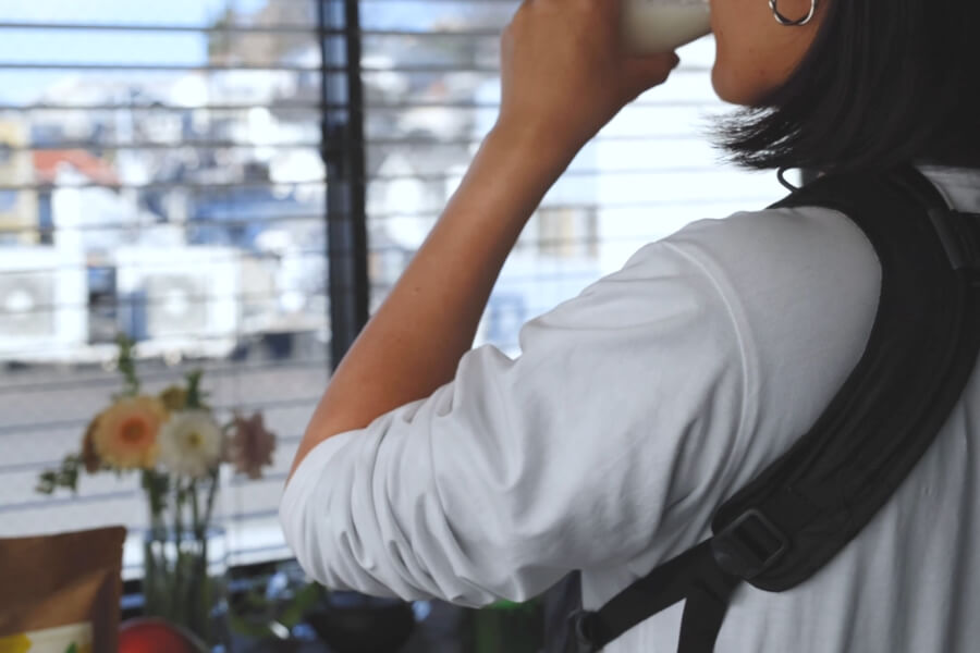 赤ちゃんを抱っこしながらマミーズプロテインで栄養補給するシーン